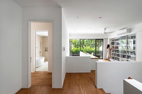 The first floor unfolds into an open study room facing the corridor’s double volume, featuring a bookshelf and a view of nature.