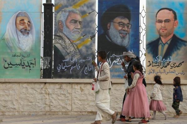 People walk past posters of former Hamas leader Ahmad Yassin, former chief of Iranian Quds Force Qassem Suleimani, Lebanon's Hezbollah chief Sayyed Hassan Nasrallah and Houthi leader Mahdi al-Mashat at the Sabeen Square in Sanaa, Yemen
