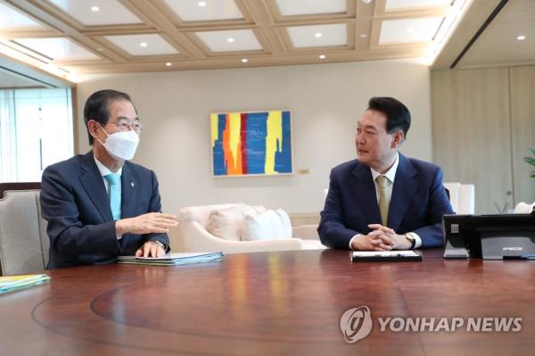 This undated file photo shows President Yoon Suk Yeol (R) talking with Prime Minister Han Duck-soo during their weekly meeting at the presidential office in Seoul. (Yonhap)